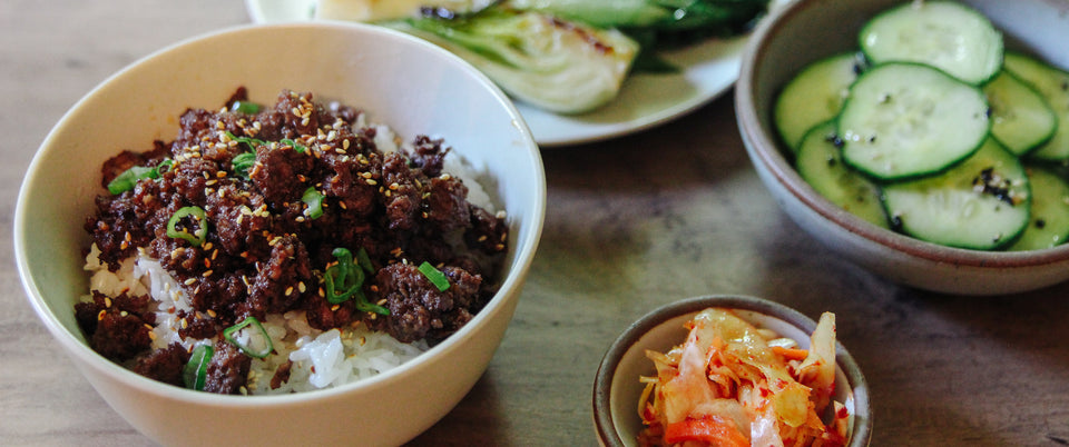 Ground Beef Bulgogi served over rice with bok choy, cucumbers, carrots, and kimchi